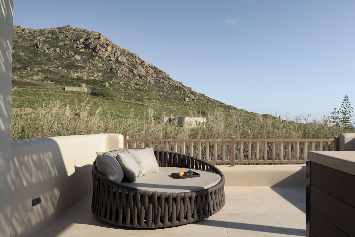 A circular outdoor seating area with cushions and a tray, overlooking a mountainous landscape.