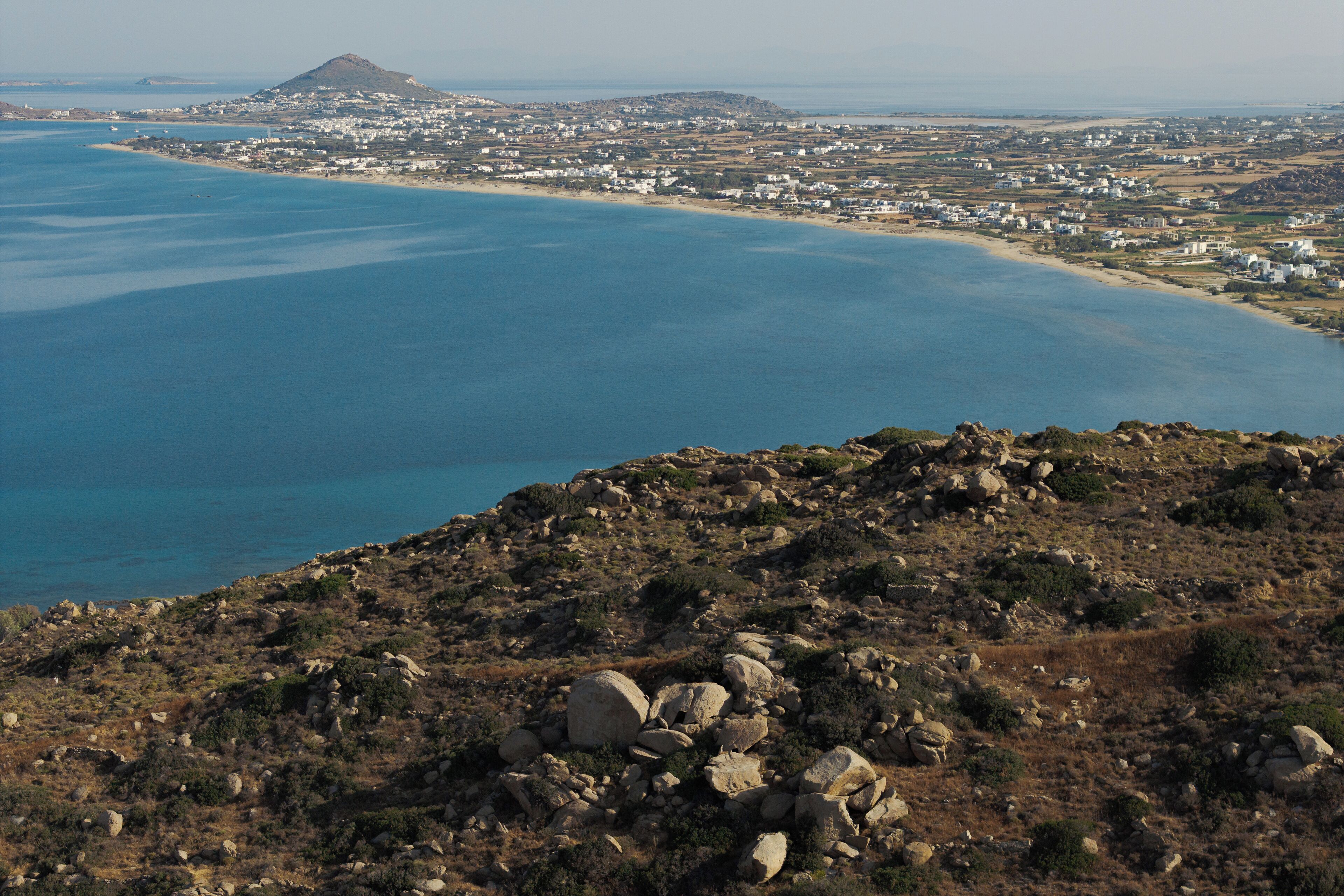 Eine Küstenlandschaft mit felsigem Gelände und Blick auf eine Stadt am Wasser.