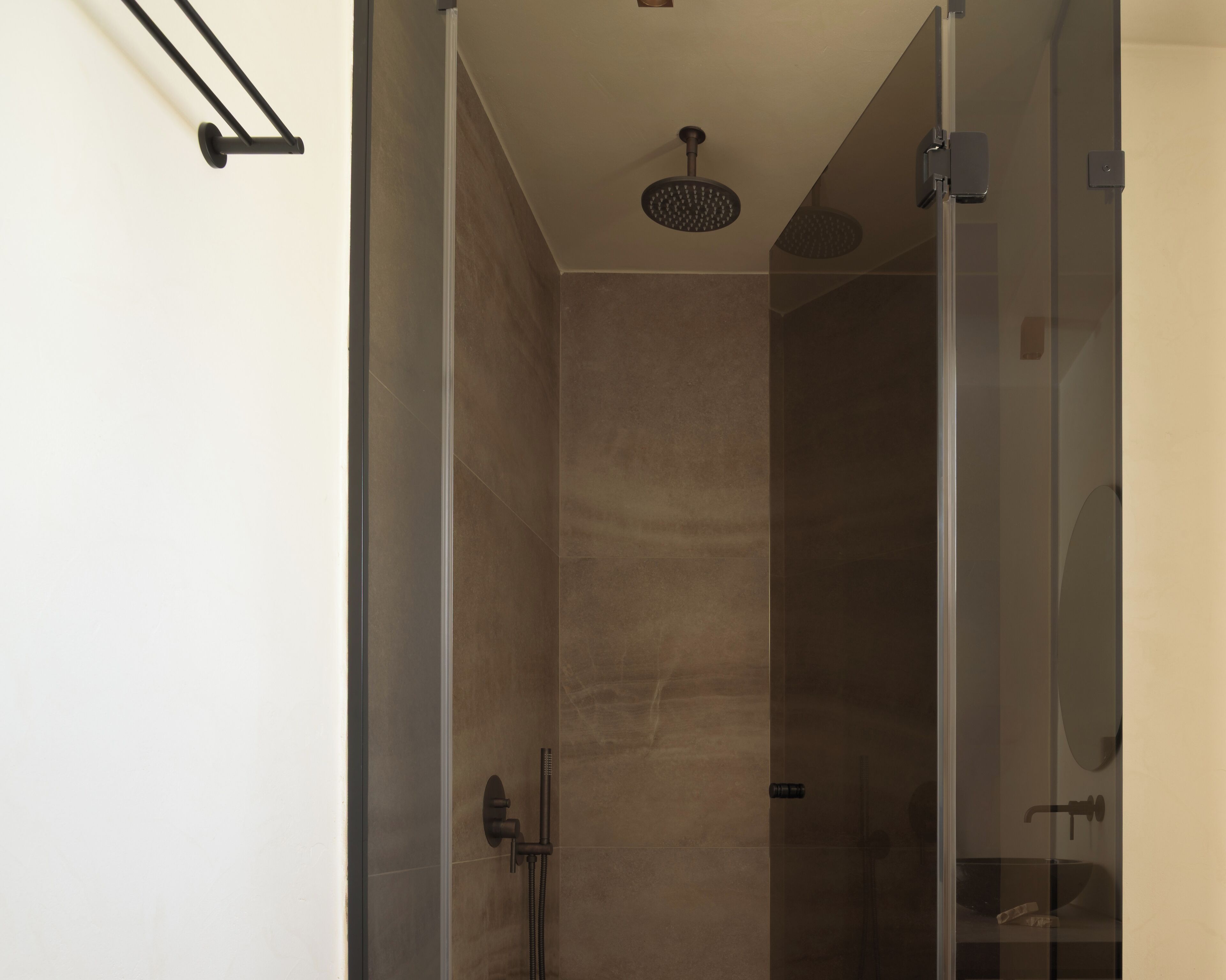 Une douche moderne dotée d’une porte en verre, d’un pommeau de douche à main et d’un robinet mural.