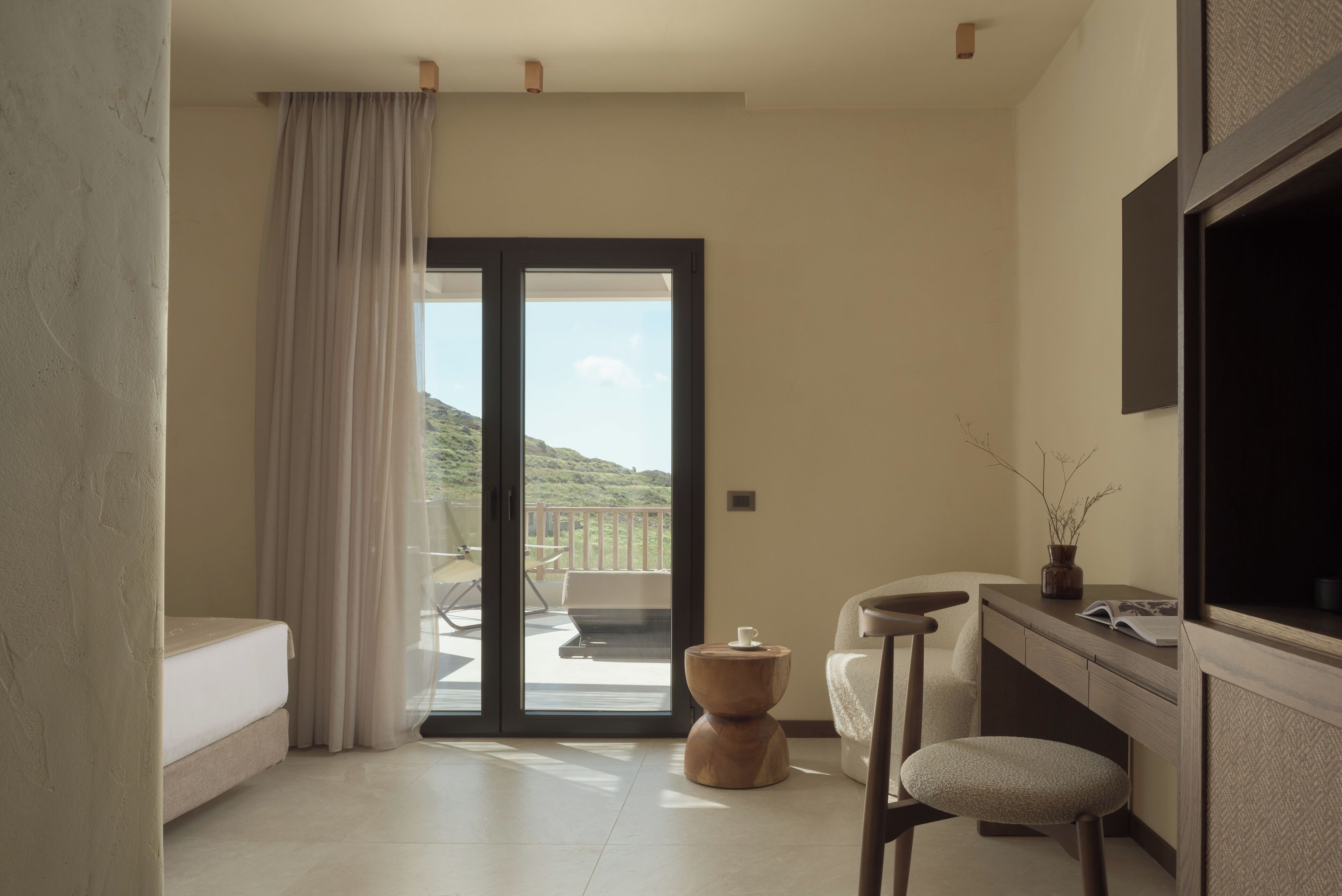 A modern bathroom with a bathtub, a vanity with a mirror, and a view of a balcony with outdoor furniture.
