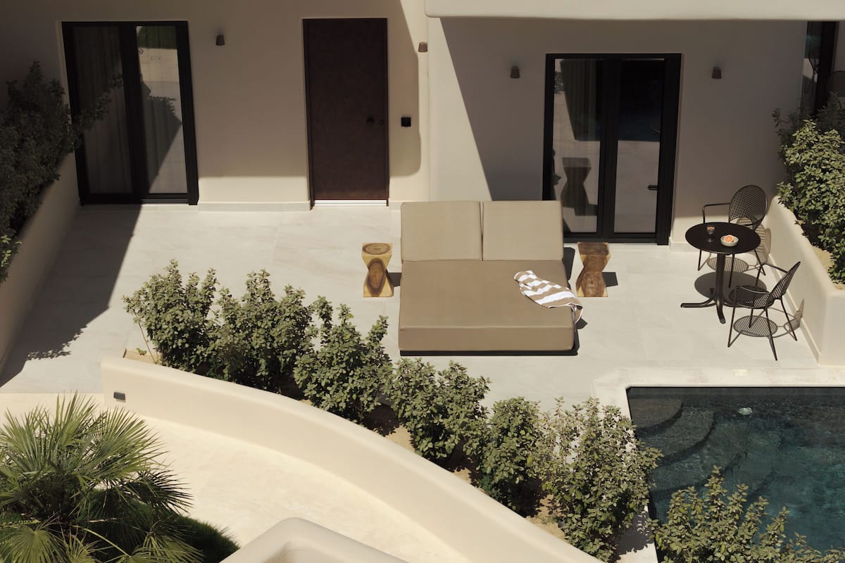 A modern outdoor living area with a pool, a sofa, and a table with chairs.