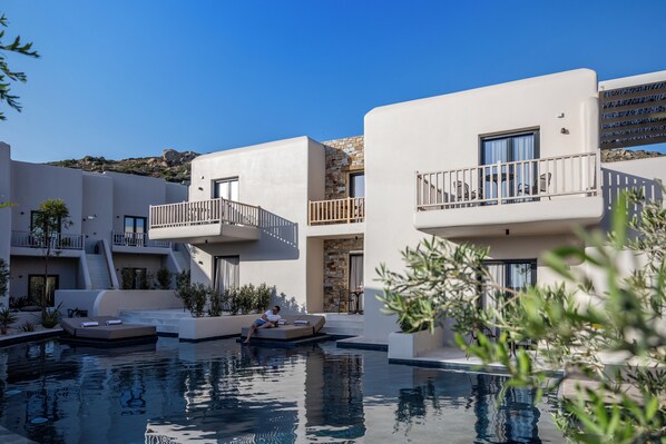 A modern resort with a swimming pool, outdoor seating, and a stone facade. - The Key (Naxos)