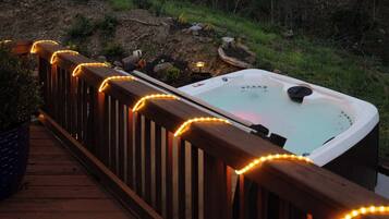 Une terrasse en bois avec un jacuzzi et des guirlandes lumineuses.