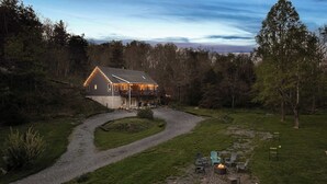 A two-story house with a porch and deck, surrounded by a wooded area. - The Haven at Turkey Run • Hot Tub, Fire Pit, Games (Strasburg)