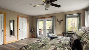 A bedroom with a large bed, a ceiling fan, a door leading to a balcony, and a wall-mounted deer head decoration. - The Haven at Turkey Run • Hot Tub, Fire Pit, Games (Strasburg)