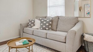 A living room with a grey sofa, a round wooden coffee table, and a mirror on the wall. - The Verde in the Fort! (Fort Worth)