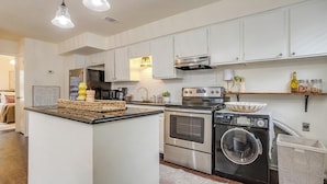 A modern kitchen with white cabinets, stainless steel appliances, and a central island. - Green Door Cutie Close to Everything in The Fort! (Fort Worth)