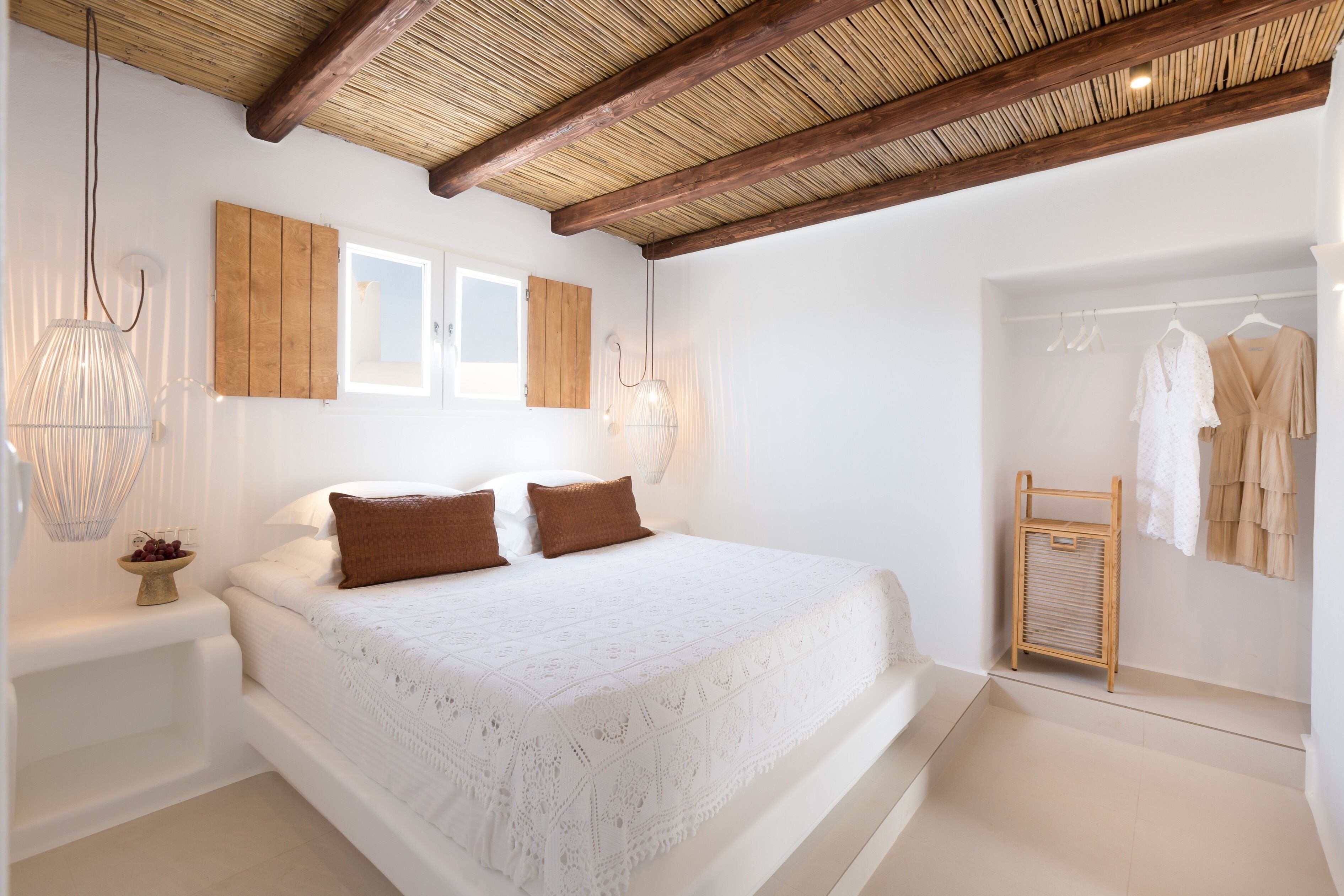 Ein Schlafzimmer mit einem großen Bett, Holzbalkendecke, einem Schrank aus Holz und einer Kleiderstange.