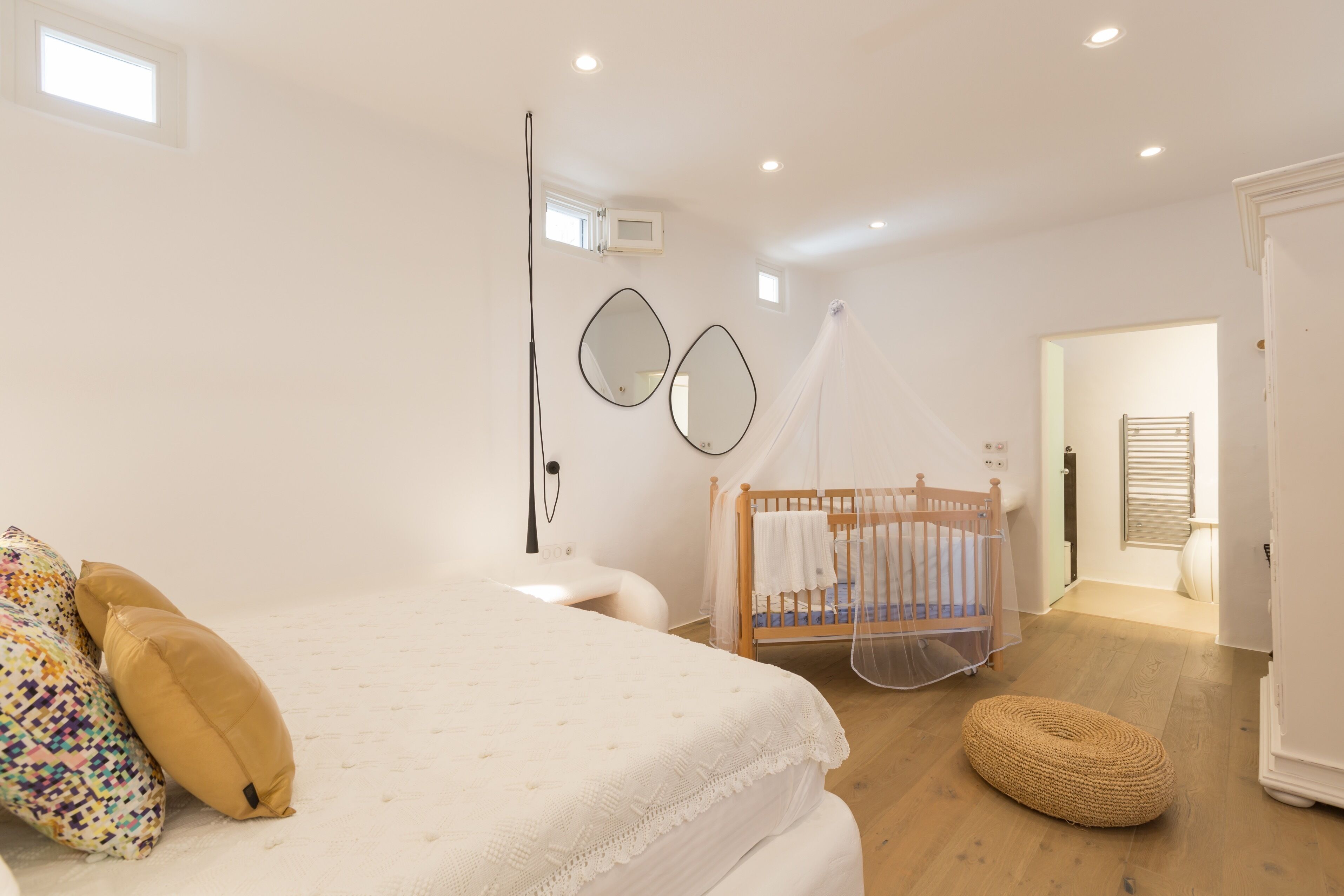 Une chambre à coucher avec un lit, une table de chevet et un berceau.
