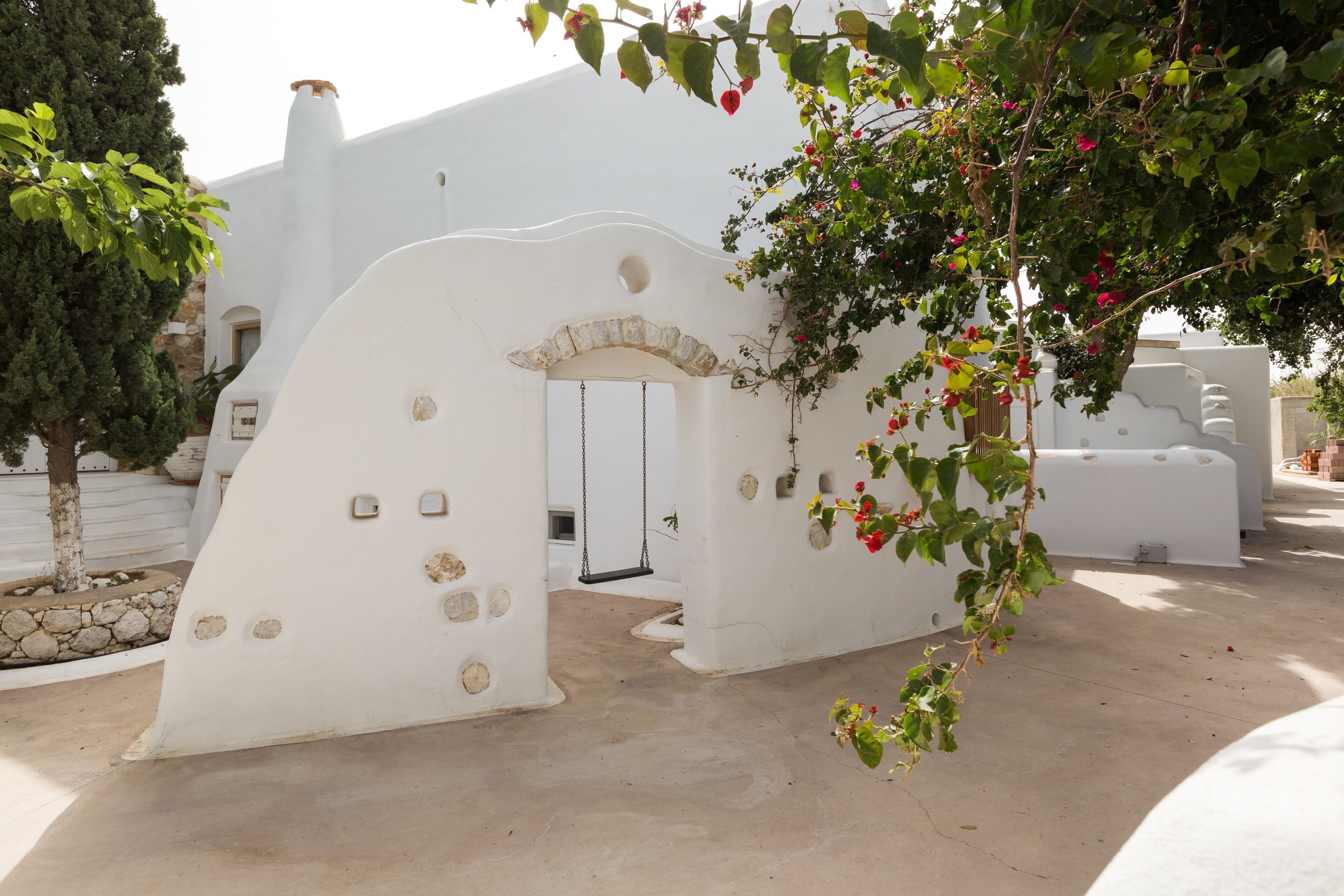 Un edificio bianco con un ingresso ad arco particolare e un'altalena.