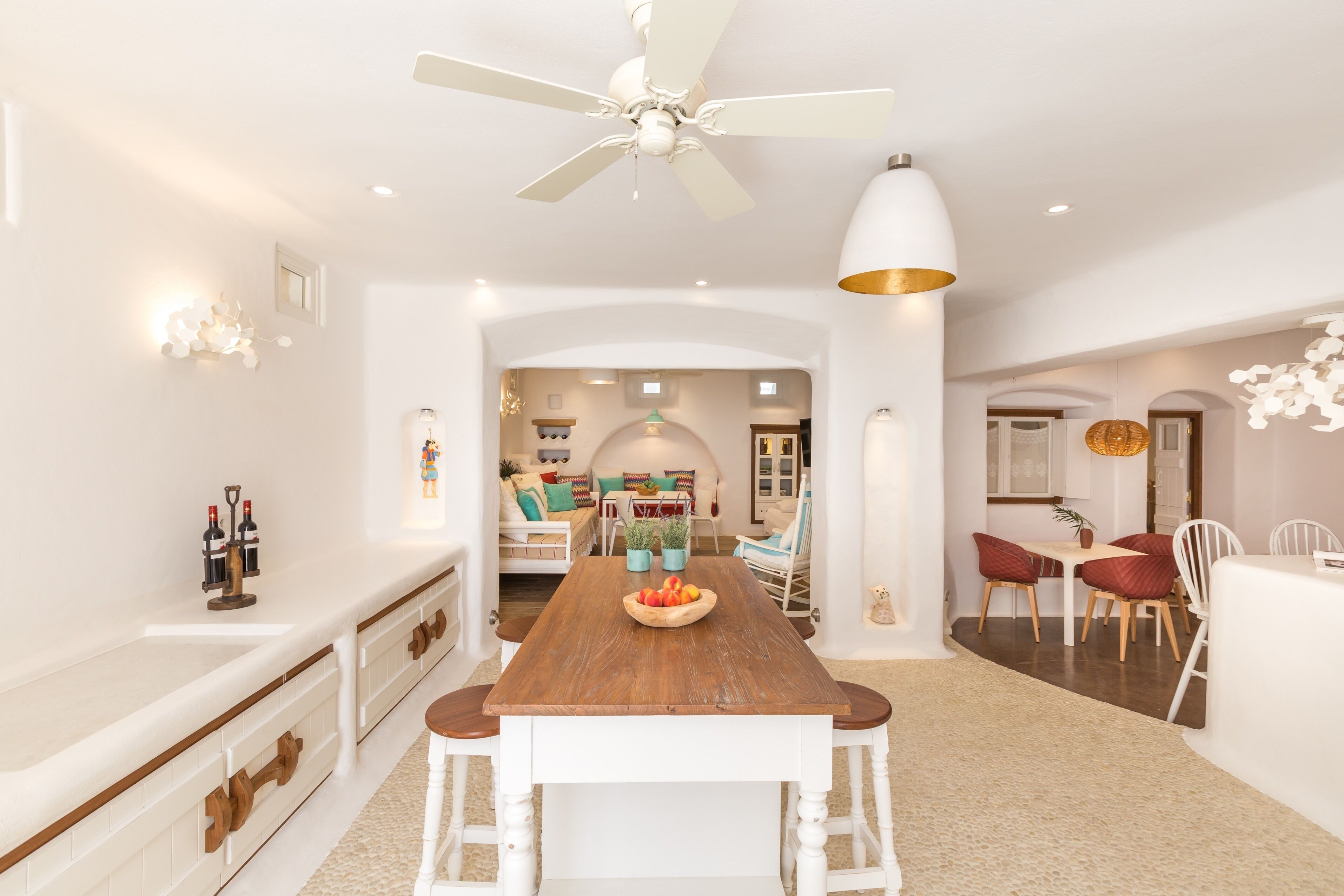 Una cocina amplia con una mesa de madera, armarios blancos y un ventilador de techo.