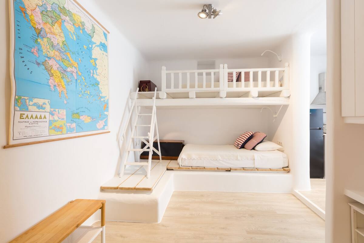 A compact room with a bunk bed, a wooden desk, and a large map on the wall.