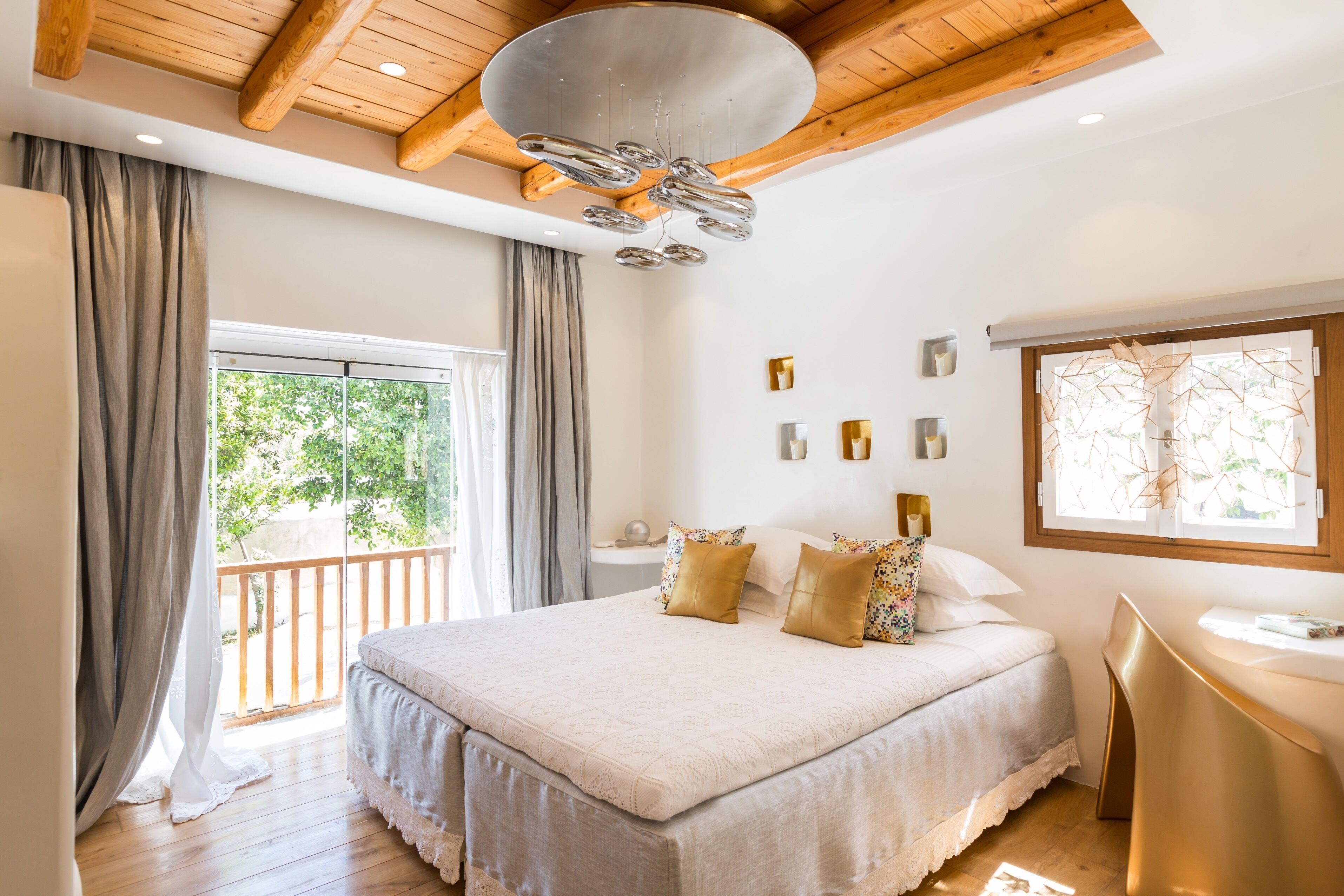 A bedroom with a large bed, a desk, and a balcony with curtains.