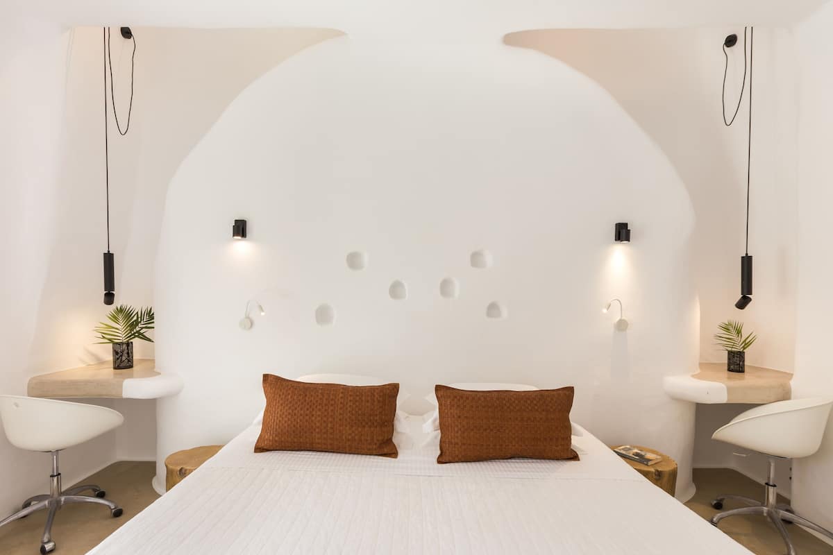 A modern bedroom with a large bed, two side tables, and a unique arched ceiling design.