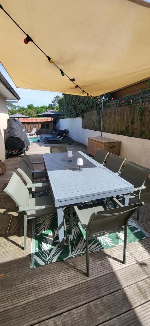Une terrasse extérieure avec une table et des chaises, un espace abrité et un barbecue.
