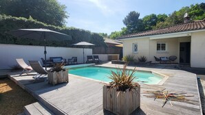 Un jardin avec une piscine, des chaises longues et des jardinières en bois.