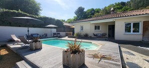 A backyard with a swimming pool, lounge chairs, and wooden planters.