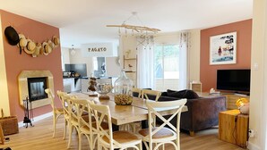 Un salon moderne comprenant un coin repas, une cheminée et une cuisine en arrière-plan.