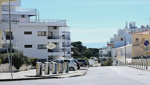 A street with modern buildings, a bar sign, and parked cars.