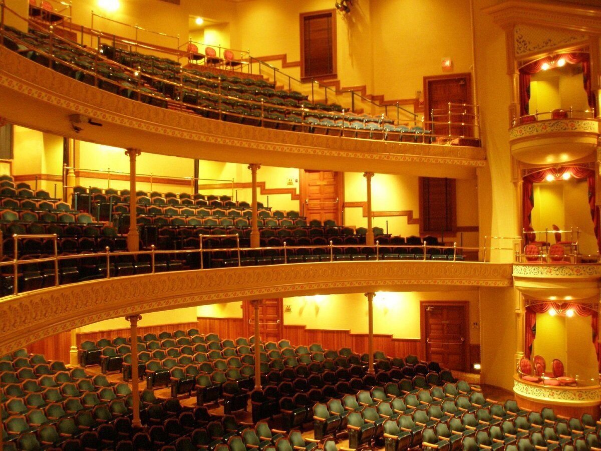A multi-level auditorium with rows of seats, a balcony, and a stage area.