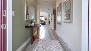 A hallway with a wooden console table, a mirror, and two framed artworks on the walls. - Amazing Home at Storey Lake 2 Minutes to Clubhouse (Kissimmee)