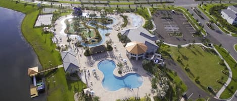 Eine Vogelperspektive zeigt ein Resort mit mehreren Schwimmbecken, einem Parkplatz und Wohnhäusern.