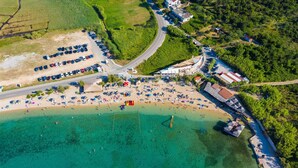 Luftaufnahme einer Küstenlandschaft mit Strand, Parkplätzen und Gebäuden.