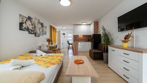 Ein modernes Hotelzimmer mit Bett, Essbereich, Küche und Fernseher.