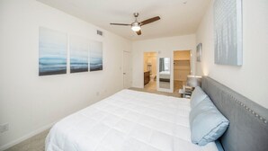 Quarto com cama grande, ventoinha no teto e obras de arte nas paredes.