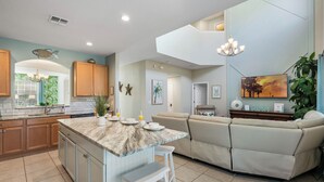 A modern kitchen with a marble island, wooden cabinets, and a built-in seating area with a sofa and bar stools.