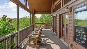 A wooden deck with outdoor seating, a glass door leading to a balcony, and a view of greenery. - Fox & Bear Lodge Near Center Hill Lake (Smithville)