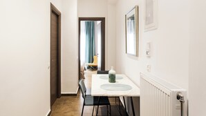 A narrow hallway leading to a dining area with a table and chairs.