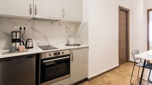 A modern kitchen with white cabinets, a built-in oven, a coffee maker, and a sink.