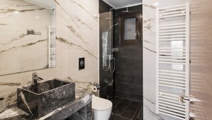 A modern bathroom with a marble vanity, a glass-enclosed shower, and a white toilet.