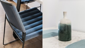 A chair with a blue cushion and a table with a ceramic vase.