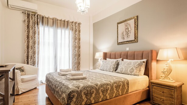 Ein Schlafzimmer mit einem großen Bett, einem Schreibtisch, einem Stuhl und einem Nachttisch mit einer Lampe.