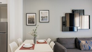Ein Essbereich mit Tisch für zwei Personen, einer grauen Couch und gerahmten Bildern an der Wand.