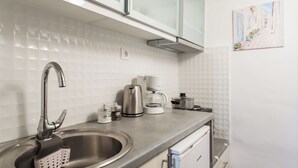 A modern kitchen with a stainless steel sink, a coffee maker, and a kettle.