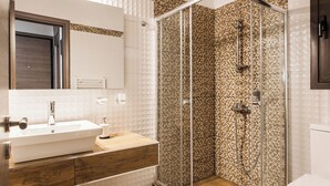 A bathroom with a glass-enclosed shower, a white sink, and a wooden vanity.