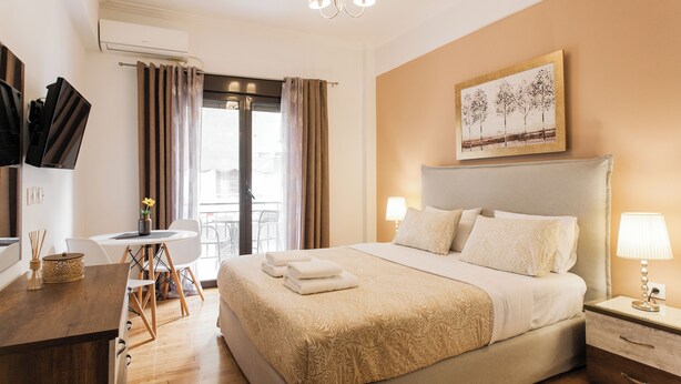 A hotel room with a bed, bedside table, lamp, and a painting on the wall.