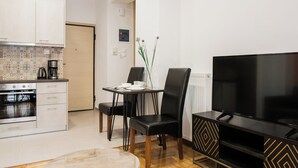 Una cocina moderna con horno empotrado, una mesa de comedor con sillas y un televisor de pantalla plana.