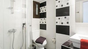 Une salle de bain avec douche, toilettes et lavabo.