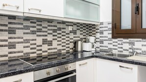 Une cuisine moderne dotée d’un plan de travail en granit noir, d’appareils électroménagers en acier inoxydable et d’un dosseret à carreaux.