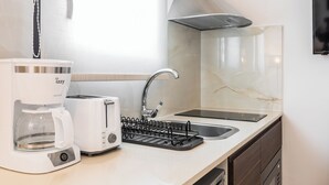 A modern kitchen with a coffee maker, toaster, sink, and a dish rack. - Oasis apartment suite (ATHENS)