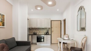 Un salon moderne avec un canapé gris, une table basse ronde et un coin repas comprenant une table blanche et des chaises en bois.