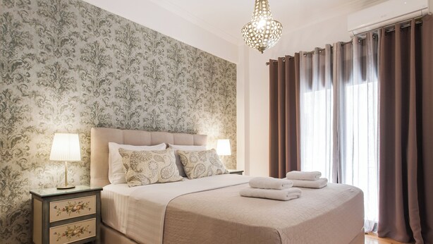 Un lit bien fait, recouvert d’une courtepointe, une lampe de chevet et une table de nuit avec des tiroirs.