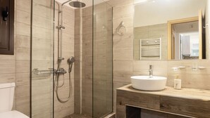 Une salle de bain moderne avec une douche à parois de verre, un meuble-lavabo en bois et un grand miroir.