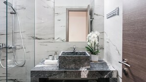 A modern bathroom with a glass-enclosed shower, a marble sink, and a potted orchid. - Romantic Studio in the Heart of Athens (ATHENS)