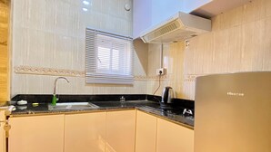 A modern kitchen with a built-in oven, a sink, and a window with blinds. - Bomma Residencies  (Abuja)