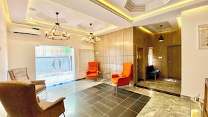A spacious lobby with a modern design, featuring a large seating area with two chairs, a marble floor, and contemporary lighting fixtures. - Bomma Residencies  (Abuja)